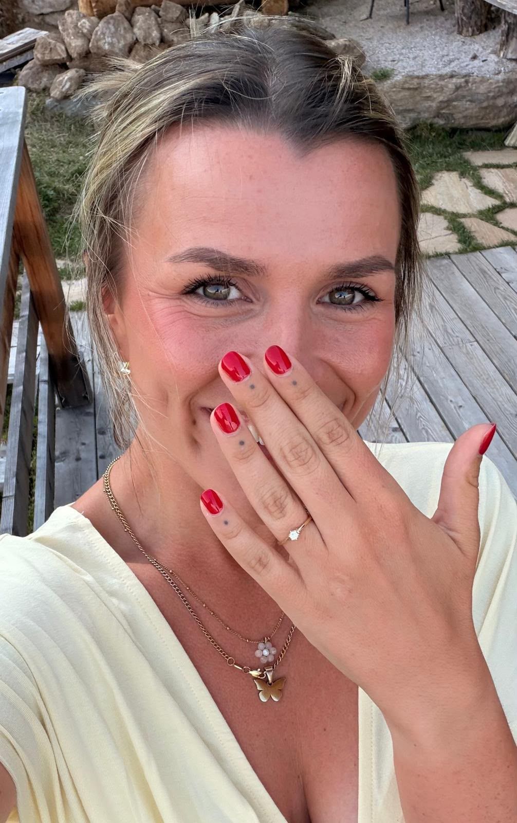 Die Hand mit dem Verlobungsring, rot lackierte Nägel